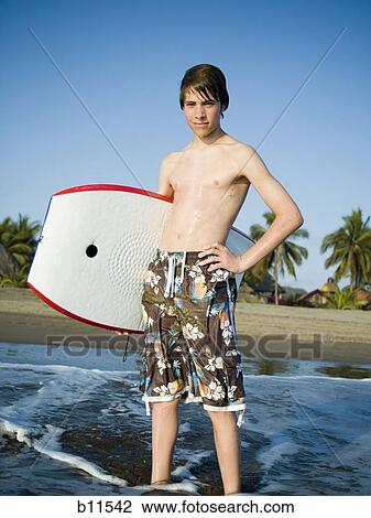 Stock Image - Boy at the beach with a boogie board. Fotosearch