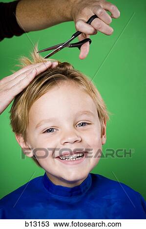 Stock Image - Boy having his hair cut smiling. Fotosearch