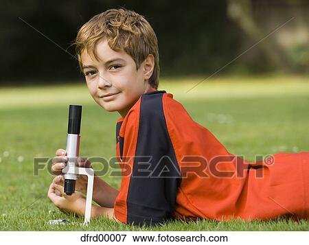 Boy lying down on grass with microscope View Large Photo Image Stock Photo - Boy lying down on grass with microscope. Fotosearch