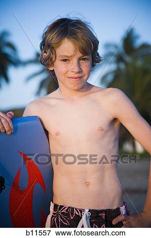 Stock Photo - Boy on beach with boogie board. Fotosearch