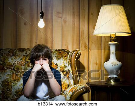 Picture - Boy on sofa with light bulb and lamp. Fotosearch