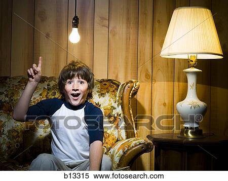 Stock Photography - Boy on sofa with light bulb and lamp pointing up. Fotosearch