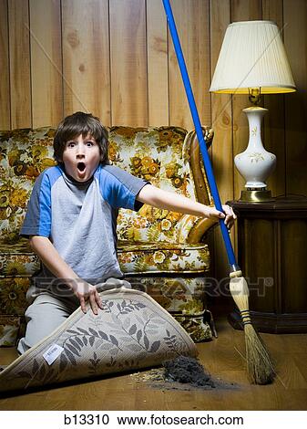 Boy sweeping dirt under rug Stock Image | b13310 | Fotosearch