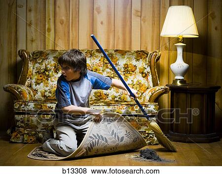 Stock Photo - Boy sweeping dirt under rug. Fotosearch