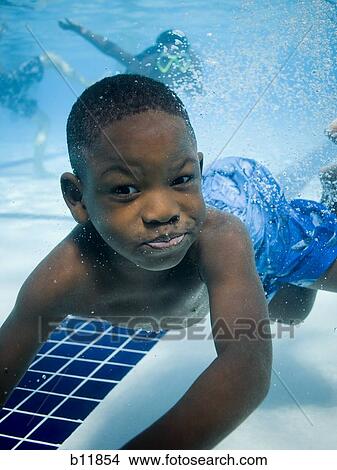 Picture - Boy swimming underwater in pool. Fotosearch