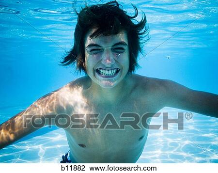 Stock Image - Boy swimming underwater in pool. Fotosearch