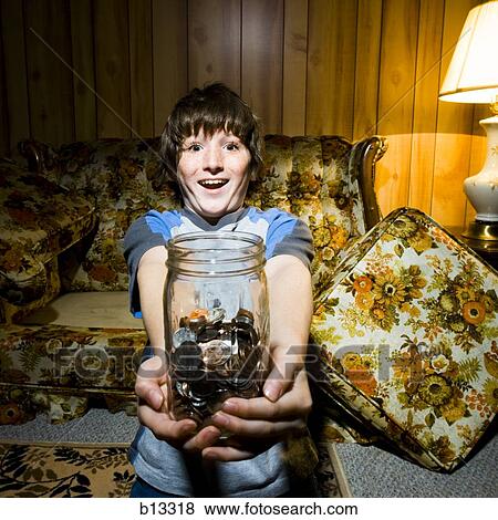Stock Photo - Boy with coin jar smiling. Fotosearch