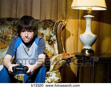 Boy with video game controller on sofa View Large Photo Image Stock Image - Boy with video game controller on sofa. Fotosearch