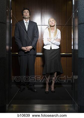Businessman and a businesswoman standing in an elevator View Large Photo Image Stock Photo - Businessman and a businesswoman standing in an elevator. Fotosearch