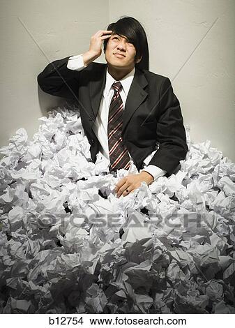 Picture - Businessman buried in mountain of crumpled papers. Fotosearch