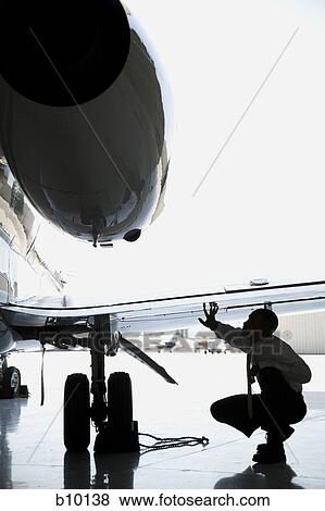 Businessman crouching and inspecting an airplane wing View Large Photo Image Stock Photo - Businessman crouching and inspecting an airplane wing. Fotosearch