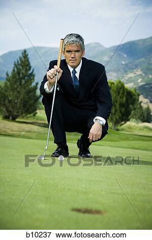 Businessman crouching on a golf course View Large Photo Image Stock Photo - Businessman crouching on a golf course. Fotosearch