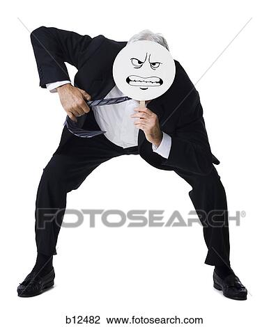 Businessman holding a determined face mask View Large Photo Image Stock Image - Businessman holding a determined face mask. Fotosearch