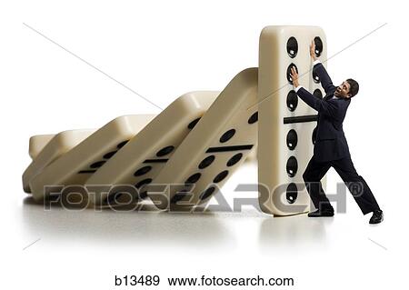 Businessman holding up falling dominoes View Large Photo Image Stock Photo - Businessman holding up falling dominoes. Fotosearch