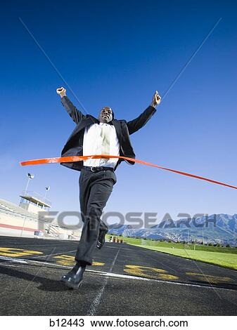 Stock Image - Businessman running and crossing finish line. Fotosearch