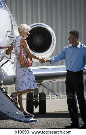 Businessman shaking hands with a businesswoman stepping down from an airplane View Large Photo Image Stock Image - Businessman shaking hands with a businesswoman stepping down from an airplane. Fotosearch