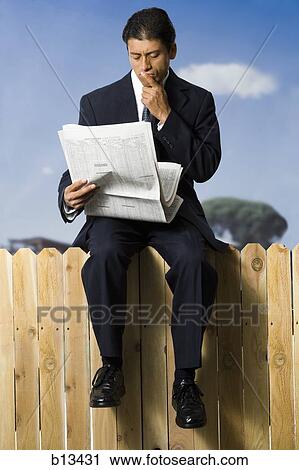 Businessman sitting on fence reading newspaper View Large Photo Image Stock Image - Businessman sitting on fence reading newspaper. Fotosearch