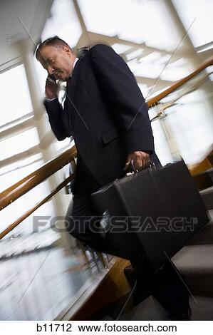 Businessman walking down stairs and talking on cell phone View Large Photo Image Stock Image - Businessman walking down stairs and talking on cell phone. Fotosearch
