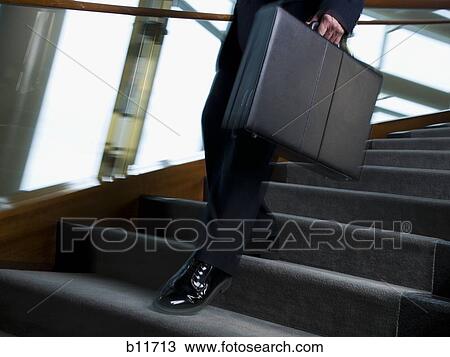 Stock Image - Businessman walking down stairs. Fotosearch