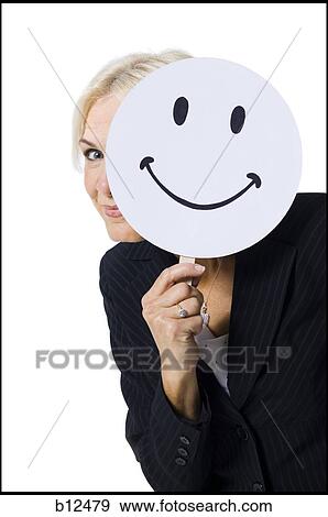 Stock Photo - Businesswoman holding a happy face mask. Fotosearch