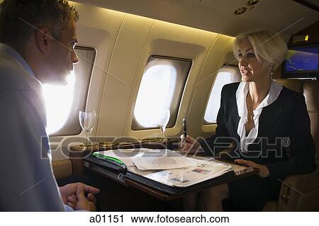 Businesswoman meeting with a businessman in an airplane View Large Photo Image Stock Image - Businesswoman meeting with a businessman in an airplane. Fotosearch