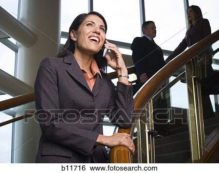 Stock Photograph - Businesswoman near stairs talking on cell phone. Fotosearch