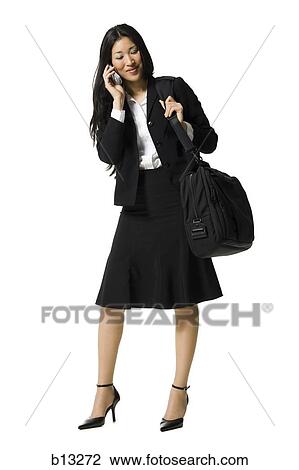 Businesswoman on cell phone with travel bag View Large Photo Image Stock Image - Businesswoman on cell phone with travel bag. Fotosearch