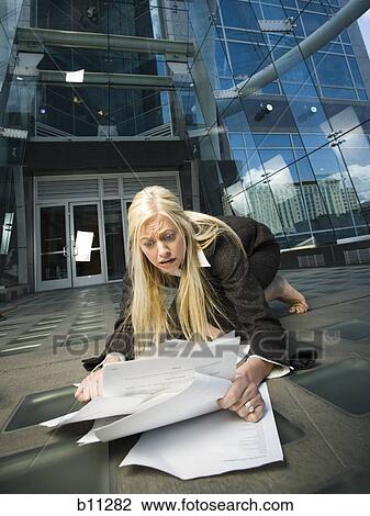 Stock Image - Businesswoman picking paperwork up off the ground. Fotosearch