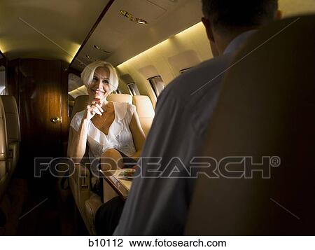 Businesswoman sitting face to face with a businessman in an airplane and smiling View Large Photo Image Stock Image - Businesswoman sitting face to face with a businessman in an airplane and smiling. Fotosearch