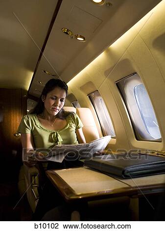 Businesswoman sitting in an airplane and reading a newspaper View Large Photo Image Stock Image - Businesswoman sitting in an airplane and reading a newspaper. Fotosearch