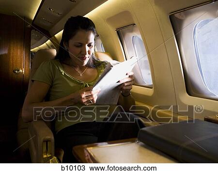 Businesswoman sitting in an airplane and reading a newspaper View Large Photo Image Stock Image - Businesswoman sitting in an airplane and reading a newspaper. Fotosearch