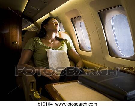 Picture - Businesswoman sleeping in an airplane. Fotosearch