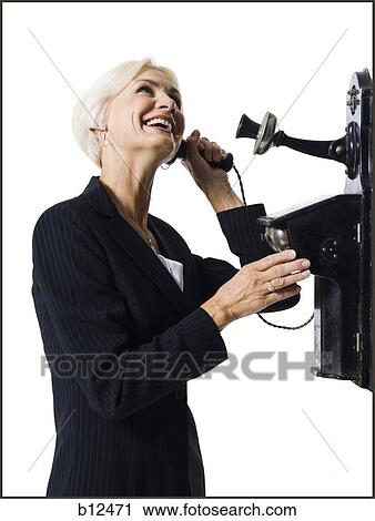 Stock Image - Businesswoman speaking on antique telephone. Fotosearch
