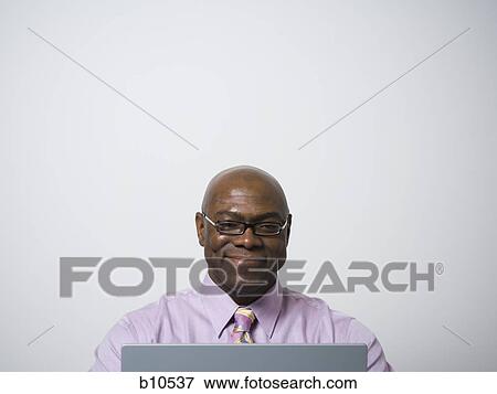 Close-up of a businessman in front of a laptop View Large Photo Image Stock Photo - Close-up of a businessman in front of a laptop. Fotosearch