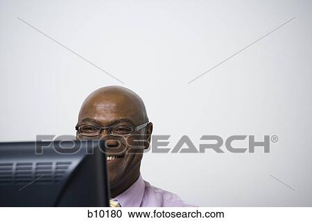 Stock Image - Close-up of a businessman using a computer and smiling. Fotosearch