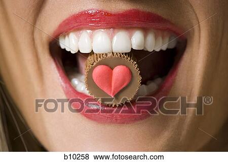 Close-up of a chocolate in a young woman's mouth View Large Photo Image Stock Photo - Close-up of a chocolate in a young woman's mouth. Fotosearch