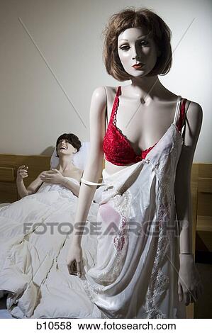 Close-up of a female mannequin half dressed with a male mannequin laughing on the bed behind View Large Photo Image Stock Photo - Close-up of a female mannequin half dressed with a male mannequin laughing on the bed behind. Fotosearch