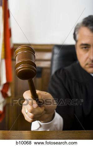 Stock Photo - Close-up of a male judge hitting a gavel on the bench. Fotosearch