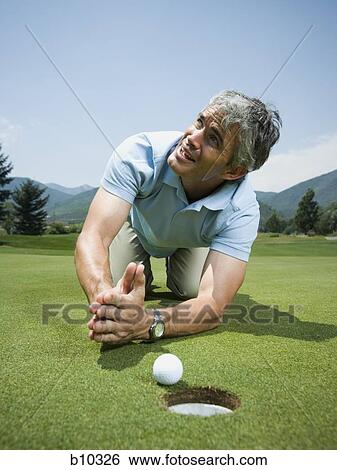 Close-up of a man kneeling in front of a golf ball near a hole and praying View Large Photo Image Stock Photograph - Close-up of a man kneeling in front of a golf ball near a hole and praying. Fotosearch