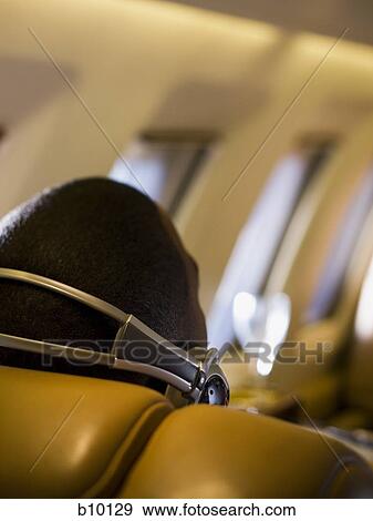 Close-up of a man listening to music on headphones in an airplane View Large Photo Image Stock Photo - Close-up of a man listening to music on headphones in an airplane. Fotosearch