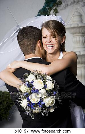 Stock Photo - Close-up of a newlywed couple embracing each other and smiling. Fotosearch