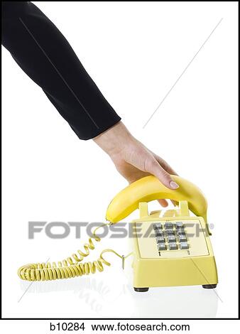 Close-up of a person's hand picking up a banana telephone receiver View Large Photo Image Picture - Close-up of a person's hand picking up a banana telephone receiver. Fotosearch