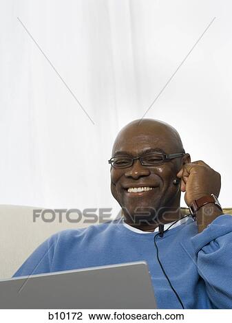 Close-up of a senior man using a laptop and smiling View Large Photo Image Stock Image - Close-up of a senior man using a laptop and smiling. Fotosearch