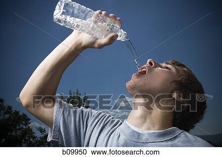 Stock Image - Close-up of a teenage boy drinking water from a water bottle. Fotosearch