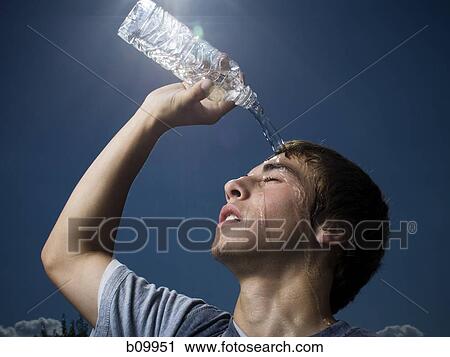 Stock Image - Close-up of a teenage boy pouring water over his head. Fotosearch