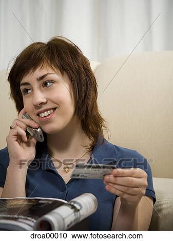 Stock Image - Close-up of a teenage girl talking on a mobile phone and holding a credit card. Fotosearch