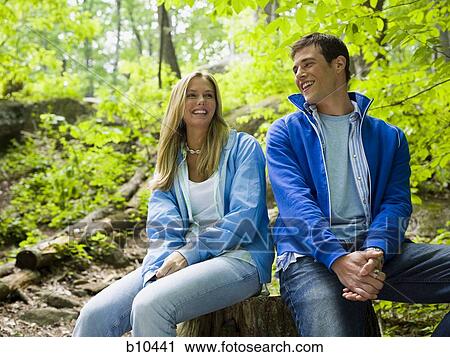 Close-up of a young couple sitting in the forest and smiling View Large Photo Image Stock Image - Close-up of a young couple sitting in the forest and smiling. Fotosearch