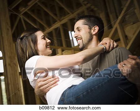 Close-up of a young man carrying a young woman and smiling View Large Photo Image Stock Image - Close-up of a young man carrying a young woman and smiling. Fotosearch