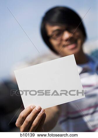 Close-up of a young man holding a blank sign and smiling View Large Photo Image Stock Photo - Close-up of a young man holding a blank sign and smiling. Fotosearch