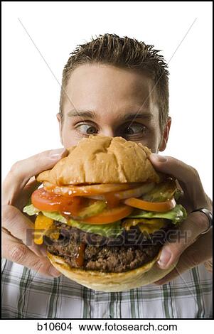 Picture - Close-up of a young man holding a hamburger. Fotosearch